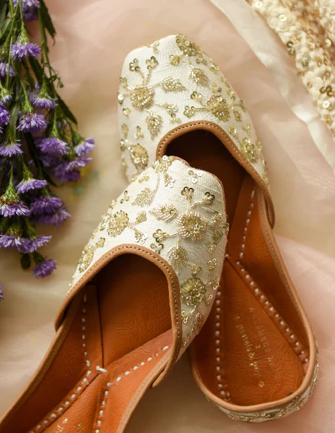 Step into Tradition: Why Punjabi Juttis are a Must-Have for Every Wardrobe In today’s ever-evolving fashion world, certain items withstand the test of time, carrying their unique charm and cultural significance across generations. Among these timeless pieces are Punjabi juttis—a symbol of elegance, artistry, and traditional craftsmanship. These versatile shoes not only celebrate the heritage of Indian craftsmanship but also bring a blend of comfort and sophistication to any outfit. Here’s why adding a pair of Punjabi juttis to your wardrobe is a true fashion essential. What Are Punjabi Juttis? An Introduction to Timeless Footwear Punjabi juttis are flat-soled shoes, often crafted from leather and elaborately embroidered, representing traditional footwear originating from Northern India. These handcrafted shoes are known for their unique designs, intricate patterns, and vibrant colors, making them a perfect blend of art and fashion. Whether paired with traditional attire or used to add flair to contemporary looks, Punjabi juttis provide a touch of cultural authenticity and elegance. A Glimpse into the History of Punjabi Juttis The origins of Punjabi juttis can be traced back to the Mughal era, where royalty would wear embellished leather shoes with delicate stitching, beadwork, and real gold or silver threads. Over time, this style spread across regions and was embraced by Punjabi artisans, who added their unique cultural influences, giving rise to the iconic juttis we see today. This historical richness has kept juttis relevant, and they are still revered as a cultural staple. Why Punjabi Juttis are Perfect for Every Occasion One of the most appealing aspects of Punjabi juttis is their versatility. These shoes can be worn to casual outings, festive celebrations, weddings, and even formal events. Their intricate embroidery and range of styles mean that they can elevate any outfit, from ethnic to modern, effortlessly. Punjabi Juttis for Weddings and Festive Events A traditional Indian wedding or festive occasion is incomplete without the addition of beautifully crafted juttis. Their ability to complement the richness of lehengas, sarees, and anarkalis makes them an essential choice for anyone looking to add a touch of elegance to their ensemble. The detailing in Punjabi juttis, such as mirror work, zari embroidery, and beaded embellishments, perfectly suits the grandeur of celebratory attire. Juttis for Casual and Everyday Wear Modern fashion enthusiasts have embraced the idea of pairing juttis with jeans, dresses, and skirts. The lightness and comfort of these shoes make them ideal for daily wear, especially in the warmer months. Simple designs in muted colors or floral patterns provide a subtle, stylish touch to any casual outfit. Craftsmanship Behind Punjabi Juttis: The Art of Handmade Perfection Each pair of Punjabi juttis is the result of hours of meticulous labor by skilled artisans, who handcraft these shoes with precision. From selecting high-quality leather to creating vibrant designs, every step is done by hand. The designs often feature floral motifs, geometric patterns, and traditional embroidery techniques like phulkari and gota patti, making each pair a work of art. Eco-Friendly and Sustainable Production The traditional process of making Punjabi juttis uses minimal machinery and involves natural materials like leather and cotton. By relying on handcrafting techniques, juttis have a lower environmental impact compared to mass-produced footwear. Supporting this sustainable practice not only promotes eco-friendly fashion but also helps preserve traditional craftsmanship. Styling Tips: How to Rock Your Punjabi Juttis Pairing with Traditional Outfits For a timeless look, Punjabi juttis pair wonderfully with traditional attire. Pairing embroidered or embellished juttis with sarees, lehengas, or salwar suits can add an extra layer of sophistication and beauty. Opt for intricate patterns for festive events, while simpler designs work well with more casual traditional wear. Adding a Cultural Twist to Western Wear Incorporating Punjabi juttis into western outfits has become a modern fashion statement. These shoes look chic with denim jeans, maxi dresses, and even office wear. For an elegant fusion look, consider pairing plain juttis with jeans and a simple blouse or go bold with brightly colored juttis to add contrast to a monochrome outfit. Choosing the Right Accessories When wearing juttis with traditional attire, complementing them with matching jewelry like jhumkas (traditional earrings) or bangles can enhance the overall look. For a western outfit, a pair of minimalist earrings or a simple bracelet can strike the right balance between traditional and modern elements. Comfort Meets Style: The Benefits of Punjabi Juttis Unlike many other types of fashionable footwear, Punjabi juttis are designed with comfort in mind. Their flat soles make them an excellent choice for long events or occasions where you’ll be on your feet for extended periods. Since they’re made of soft leather, juttis gradually adapt to the shape of your feet, providing a custom fit over time. Breathable and Weather-Appropriate The leather and cotton materials used in making Punjabi juttis are ideal for warm weather, allowing your feet to breathe while keeping them comfortable. These shoes are also easy to wear in cooler weather when paired with warm clothing, making them versatile for different climates. Maintaining Your Punjabi Juttis: Care Tips To keep your Punjabi juttis looking their best, it’s essential to care for them properly. Avoid Moisture: Since most juttis are made from leather, avoid prolonged exposure to water, which can damage the leather and embroidery. Use a Soft Brush for Cleaning: Gently brush off dust and dirt using a soft brush or cloth to maintain the shine and vibrancy of your juttis. Store Properly: To keep them from losing their shape, stuff your juttis with tissue paper or cloth when not in use and store them in a cool, dry place. Punjabi Juttis: The Ethical Choice in Fashion Investing in Punjabi juttis also supports traditional artisans and local businesses. By choosing these handcrafted shoes over mass-produced items, you contribute to the preservation of cultural art forms and provide income for skilled craftspeople. This conscious choice not only enhances your style but also promotes a responsible, sustainable approach to fashion. Where to Find Authentic Punjabi Juttis Finding a pair of authentic, high-quality Punjabi juttis can be an exciting journey in itself. Traditional markets in cities like Amritsar, Jaipur, and Delhi offer an extensive variety of juttis that you can explore and handpick. Many online platforms also provide authentic options crafted by skilled artisans, often with worldwide shipping, making it easier than ever to add a pair to your wardrobe. Conclusion: Embrace Tradition with a Modern Twist Adding Punjabi juttis to your wardrobe is more than just a fashion choice; it’s a celebration of culture, art, and heritage. With their versatility, timeless appeal, and unique craftsmanship, Punjabi juttis can transform any outfit and bring a touch of elegance to every step. Step into tradition with these stunning shoes and experience the blend of comfort, style, and cultural pride that only Punjabi juttis can provide.