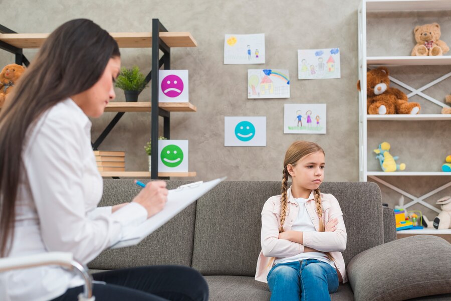 depressed-girl-sitting-sofa-with-female-psychologist-writing-note-clipboard_